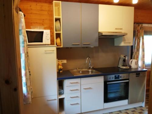 a kitchen with white cabinets and a sink and a microwave at Ferienhaus Baden in Simmelsdorf
