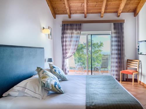 a bedroom with a large bed and a balcony at Vilafoia in Monchique