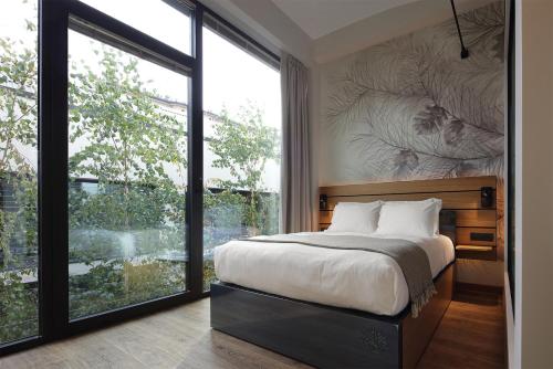 a bedroom with a bed and a large window at VERSOVERDE HOTEL Alzaia Naviglio Grande in Milan