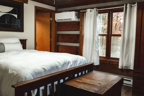 1 dormitorio con cama, mesa y ventana en Serenity Ridge Cabin at 36 North - Hot Tub, en Purlear
