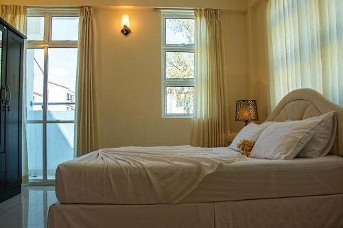 a bedroom with a white bed with a window at Beach Palace in Hulhumale