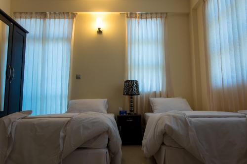 two beds in a hotel room with white curtains at Beach Palace in Hulhumale