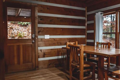een houten eetkamer met een tafel en een raam bij Deer Run Cabin at 36 North - Hot Tub in Purlear