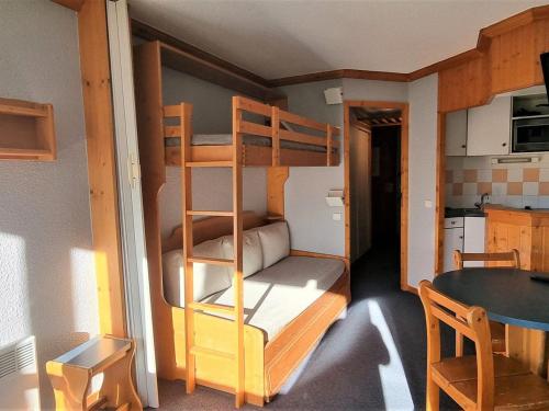 Ce lit superposé se trouve dans une petite chambre avec une table. dans l'établissement Studio lumineux divisible - Pied des pistes - Balcon exposé sud - FR-1-181-2608, à Aime La Plagne