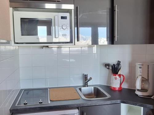 une cuisine avec un évier et un micro-ondes dans l'établissement Studio confortable au pied des pistes, balcon, animaux admis - FR-1-181-2562, à Aime La Plagne
