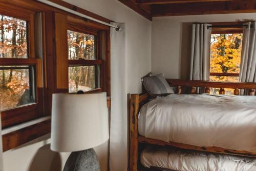 een slaapkamer met een bed, een lamp en ramen bij Deer Run Cabin at 36 North - Hot Tub in Purlear