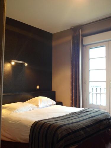 a bedroom with a bed with a black wall at Hôtel Restaurant du Lac in Combourg