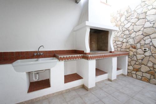 baño con lavabo y pared de piedra en Villa Lata, en Marina San Gregorio