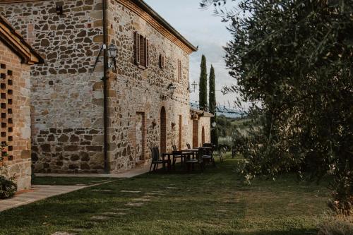 a stone building with a table and chairs in a yard at Agriturismo Belagaggio in Montefollonico