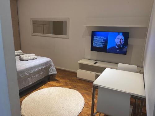Habitación con cama y TV en la pared. en Depto ubicado en Recoleta en Buenos Aires