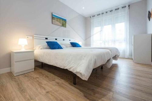 1 dormitorio blanco con 1 cama grande con almohadas azules en Apartamento Juan XXIII, en Gijón