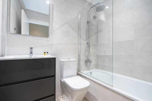 y baño blanco con aseo y ducha. en Apartamento Juan XXIII, en Gijón