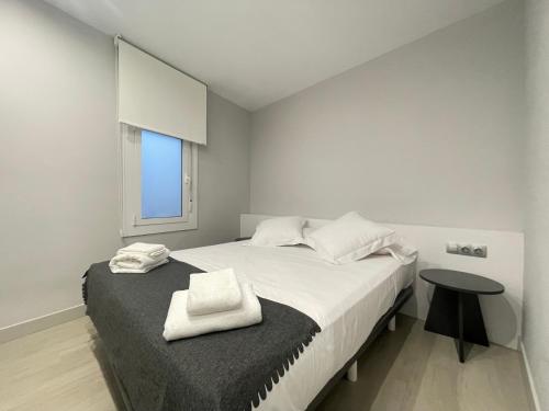 Apartaments Voramar Roses في روساس: غرفة نوم بسرير ابيض مع طاولة ونافذة