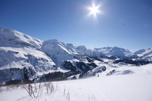 a snow covered mountain range with the sun in the sky at Soldanella in Lech am Arlberg