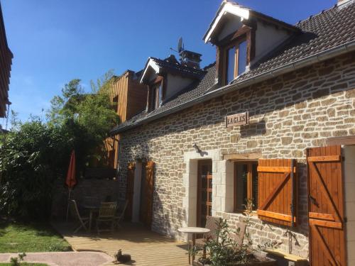 a brick house with a wooden porch and a patio at Les Crinieres En Brie in Saint-Ouen-en-Brie