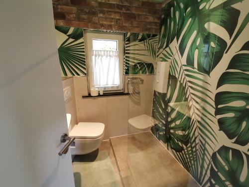 a bathroom with a toilet and green leaves on the wall at adBs Ferienhaus in Winterberg