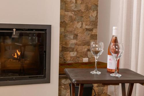 a bottle of wine and two glasses on a table next to a fireplace at Kyra’s House in Neraïdochóri