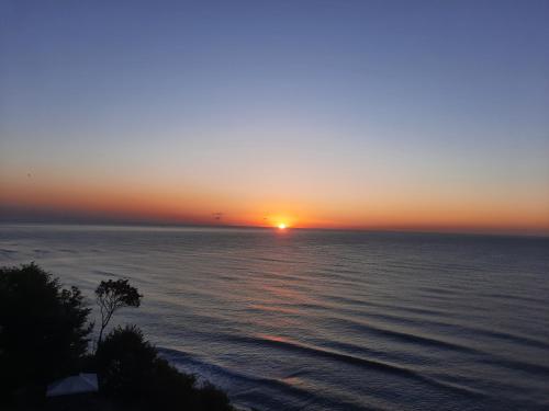 una puesta de sol sobre el océano con el sol en la distancia en Byala Vista Cliff Apartments en Byala
