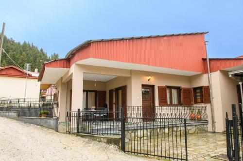 een huis met een rood dak en een hek bij Kyra’s House in Neraidochori