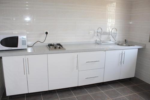 a white kitchen with a microwave and a sink at GOLF VIEW RESIDENCE_STUDIO in Yaoundé