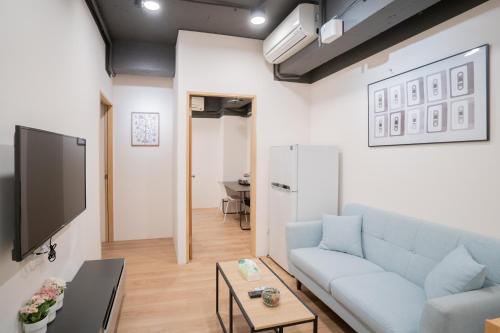 a living room with a couch and a tv at HotelsHere - Ximen in Taipei