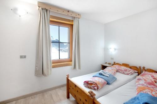 1 dormitorio con cama y ventana en Appartamento Vacanze Matteo, en Livigno