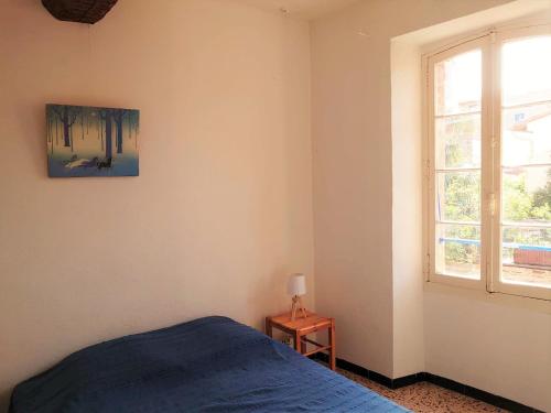 une chambre avec un lit bleu et une fenêtre dans l'établissement 5COMA2 Appartement proche plage, à Collioure