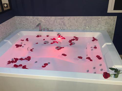 una vasca da bagno piena di rose rosse in bagno di L'Eclipse maison romantique avec Jacuzzi 