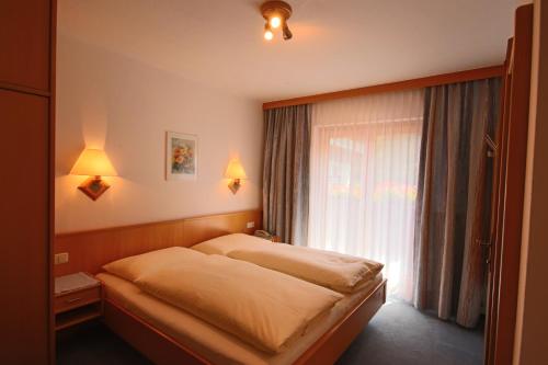a bedroom with a bed and a window at Pension Riedlsperger in Saalbach Hinterglemm