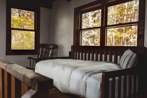 ein Schlafzimmer mit einem Bett und zwei Fenstern in der Unterkunft Creekside Overlook at 36 North Cabin - Fireplace in Purlear