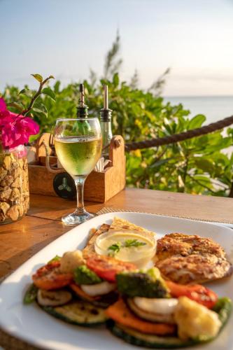 a plate of food on a table with a glass of wine at Aya Beach Resort in Kizimkazi