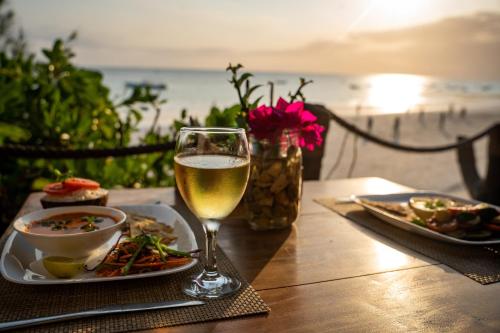 a table with a plate of food and a glass of wine at Aya Beach Resort in Kizimkazi