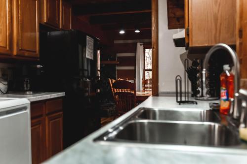 una cucina con lavello in acciaio inossidabile e mobili in legno di Blueberry Hideaway at 36 North Cabin - Hot Tub a Purlear