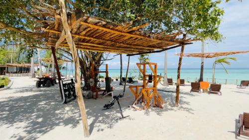 a beach with a wooden umbrella and chairs on the sand at Aya Beach Resort in Kizimkazi