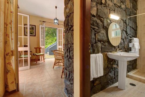 a stone bathroom with a sink and a stone wall at Casa Catarina in Junqueira