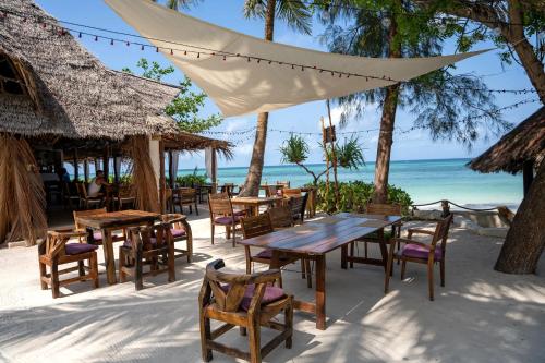 a restaurant on the beach with tables and chairs at Aya Beach Resort in Kizimkazi