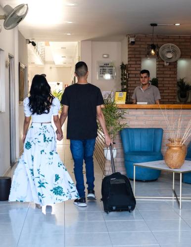 a man and a woman walking with a suitcase at Hotel Bella Isa in La Dorada