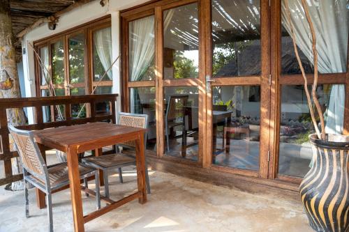a wooden table and chairs in a room with windows at Aya Beach Resort in Kizimkazi