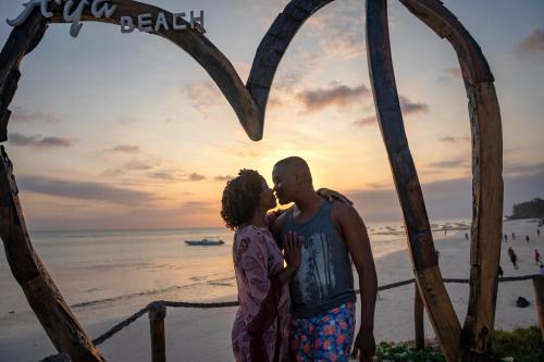 a couple kissing in front of a heart sign on the beach at Aya Beach Resort in Kizimkazi