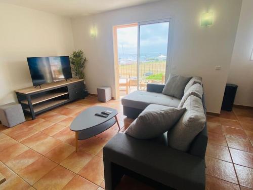 un soggiorno con divano e TV a schermo piatto di "T4 Anghjula Santa" proche du port avec vue mer a Sari Solenzara