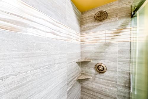 a bathroom with a shower with white tiles at Hale Ono Loa Condo in Kahana