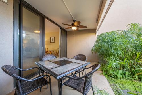 a patio table with chairs and a ceiling fan at Hale Ono Loa Condo in Kahana