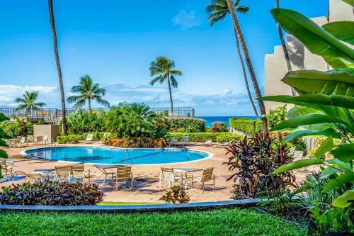 a pool with chairs and the ocean in the background at Hale Ono Loa Condo in Kahana