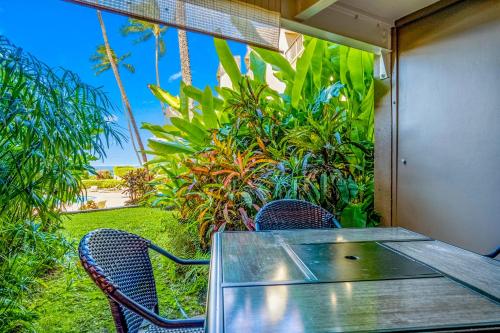 a glass table and chairs with a view of the ocean at Hale Ono Loa Condo in Kahana