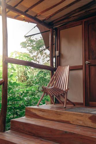 a wooden bench sitting on the porch of a house at Destino Mío Mayan Jungle Retreat in Tekit