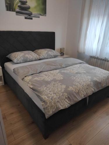 a bedroom with a bed with a blanket and pillows at Apartman NADA in Slavonski Brod