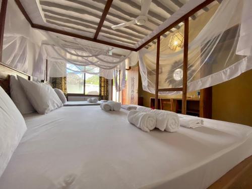 un grande letto bianco con tre asciugamani arrotolati di Zuzanu house a Nungwi