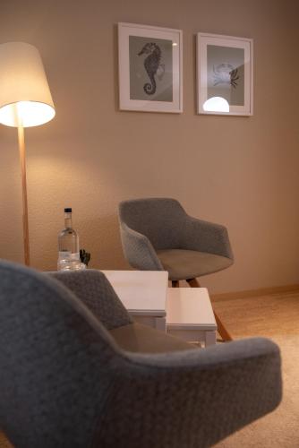 a living room with two chairs and a table and a lamp at Das Anni's in Wangerland