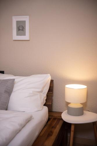 a bed with a table with a lamp next to it at Das Anni's in Wangerland