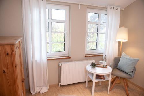 a room with a table and a chair and two windows at Das Anni's in Wangerland